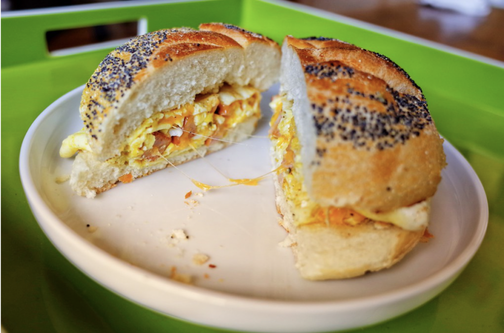 A bacon, egg, and cheese sandwich pulling apart into two halves with a delectable cheese pull. 